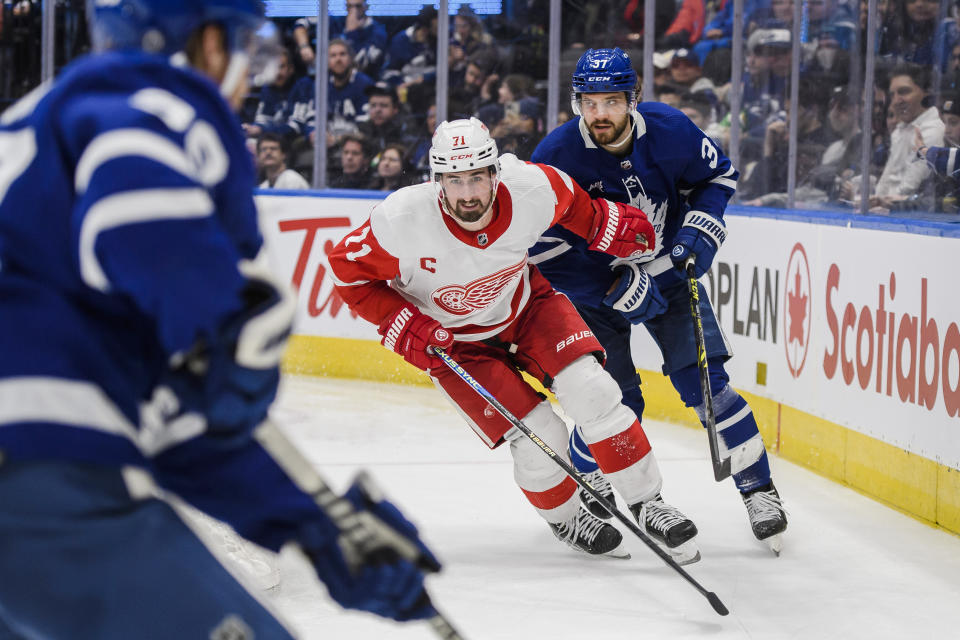 Detroit Red Wings center Dylan Larkin (71) and Toronto Maple Leafs defenseman Timothy Liljegren (37) chase the puck behind the Maple Leafs net during the third period of an NHL hockey game Saturday, Jan. 7, 2023, in Toronto. (Christopher Katsarov/The Canadian Press via AP)