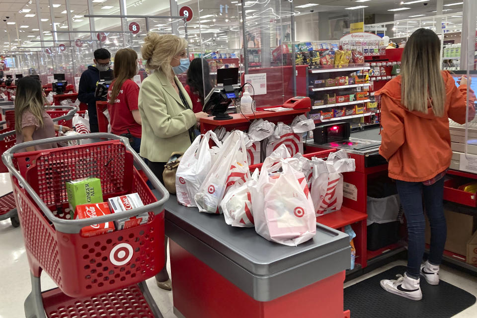 FILE - A customer wears a mask as she waits to get a receipt at a register in Target store in Vernon Hills, Ill., May 23, 2021. Americans cut their spending unexpectedly in May compared with the month before, underscoring how surging inflation on daily necessities like gas is causing them to be more cautious about buying discretionary items. (AP Photo/Nam Y. Huh, File)