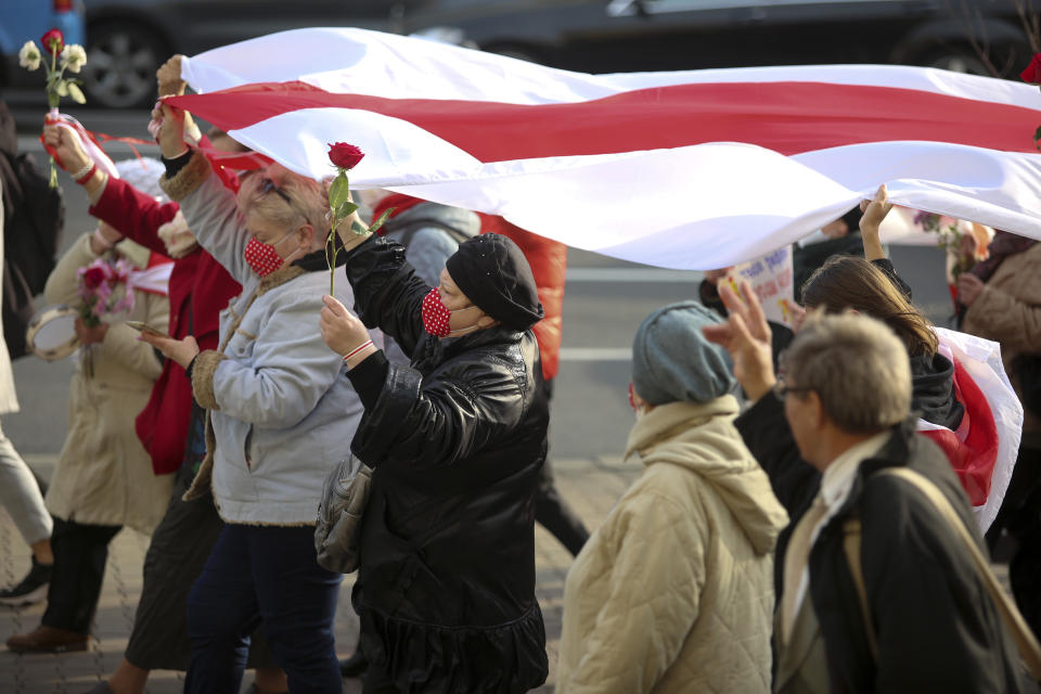 FILE - In this Monday, Oct. 26, 2020 file photo, people, most of them pensioners, carry a big old Belarusian national flag during an opposition rally to protest the official presidential election results in Minsk, Belarus. Belarus President Alexander Lukashenko has relied on massive arrests and intimidation tactics to hold on to power despite nearly three months of protests sparked by his re-election to a sixth term, but continuing protests have cast an unprecedented challenge to his 26-year rule. (AP Photo, File)