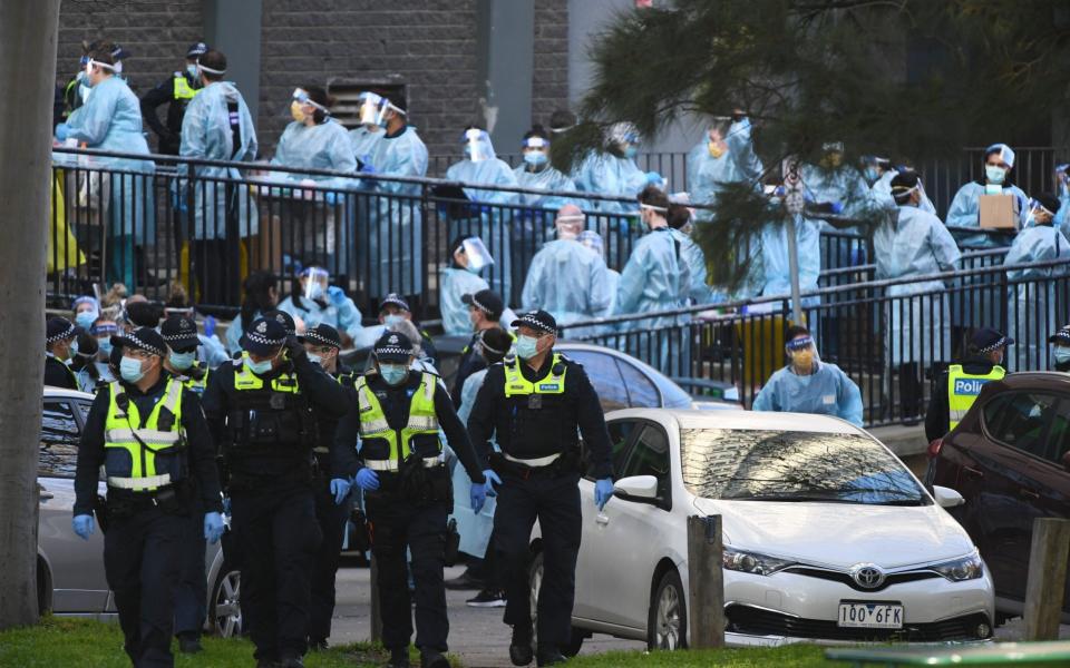 Victoria Police officers and healthcare workers congregate outside a public housing tower in North Melbourne, Australia - JAMES ROSS/EPA-EFE/Shutterstock