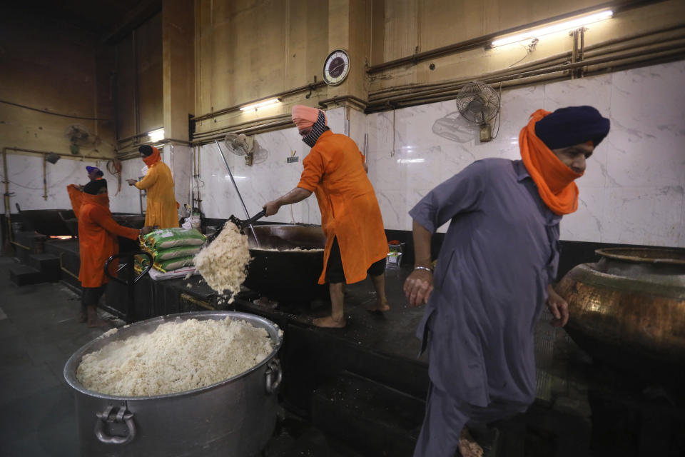 A Sikh volunteer scoops out cooked rice into a large vessel in the kitchen hall of the Bangla Sahib Gurdwara in New Delhi, India, Sunday, May 10, 2020. The Bangla Sahib Gurdwara has remained open through wars and plagues, serving thousands of people simple vegetarian food. During India's ongoing coronavirus lockdown about four dozen men have kept the temple's kitchen open, cooking up to 100,000 meals a day that the New Delhi government distributes at shelters and drop-off points throughout the city. (AP Photo/Manish Swarup)