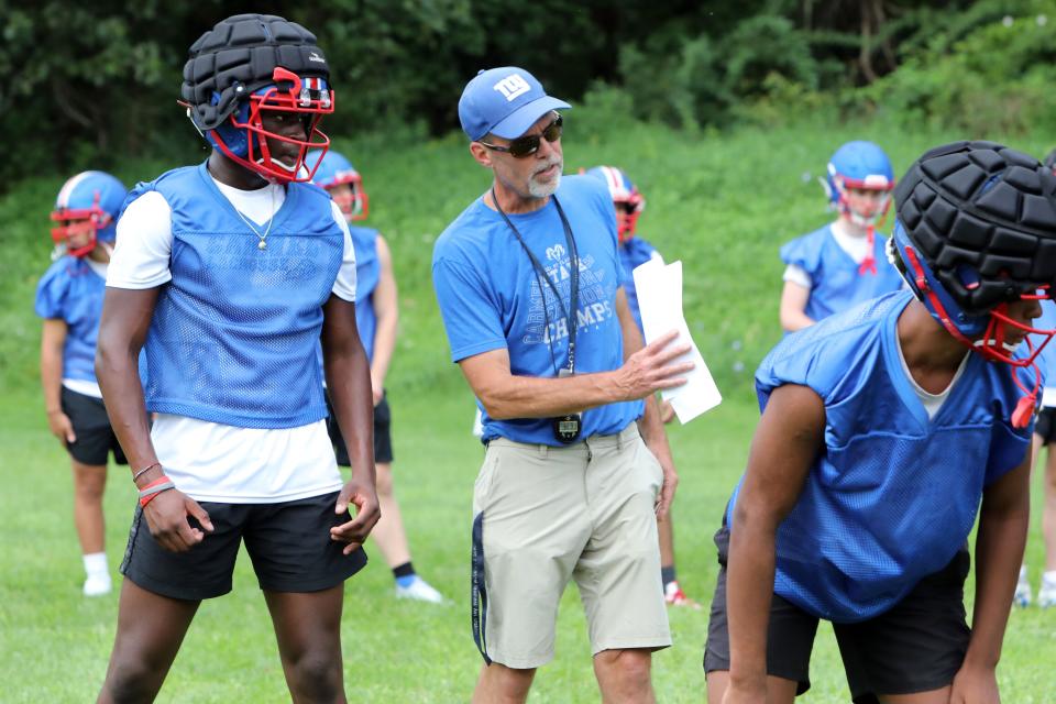 Carmel head coach Todd Cayea speaks with junior Tamba Kassoh during the first day of football practice Aug. 21, 2023 at Carmel High School.
