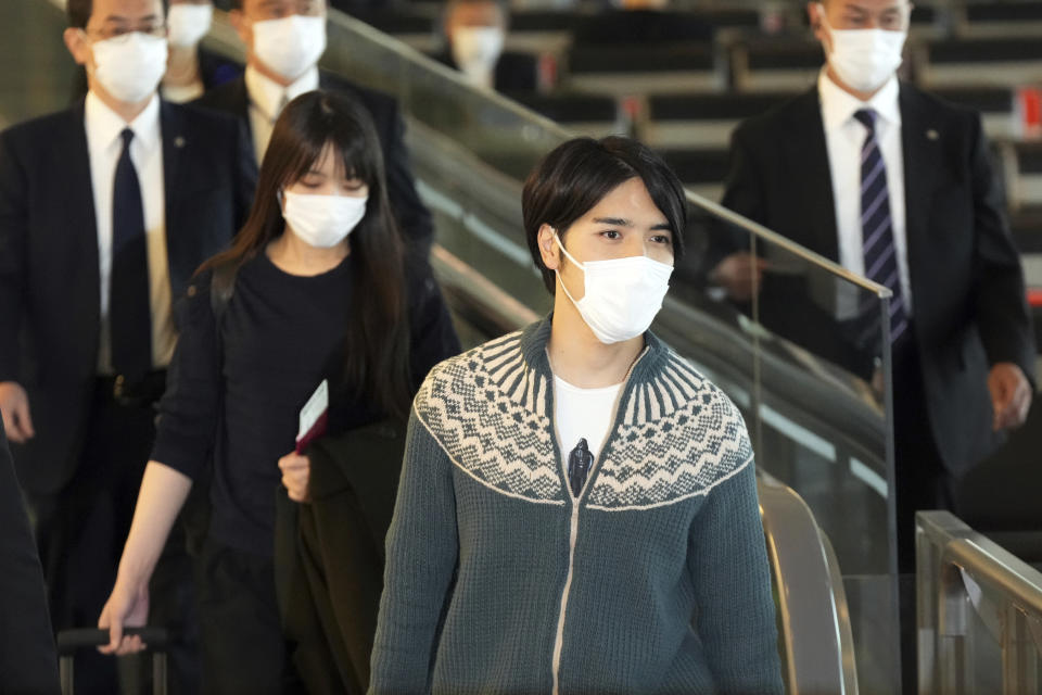 Japan's former Princess Mako, left, the elder daughter of Crown Prince Akishino, and her husband Kei Komuro, right, walk to board an airplane to New York Sunday, Nov. 14, 2021, at Tokyo International Airport in Tokyo. (AP Photo/Eugene Hoshiko)