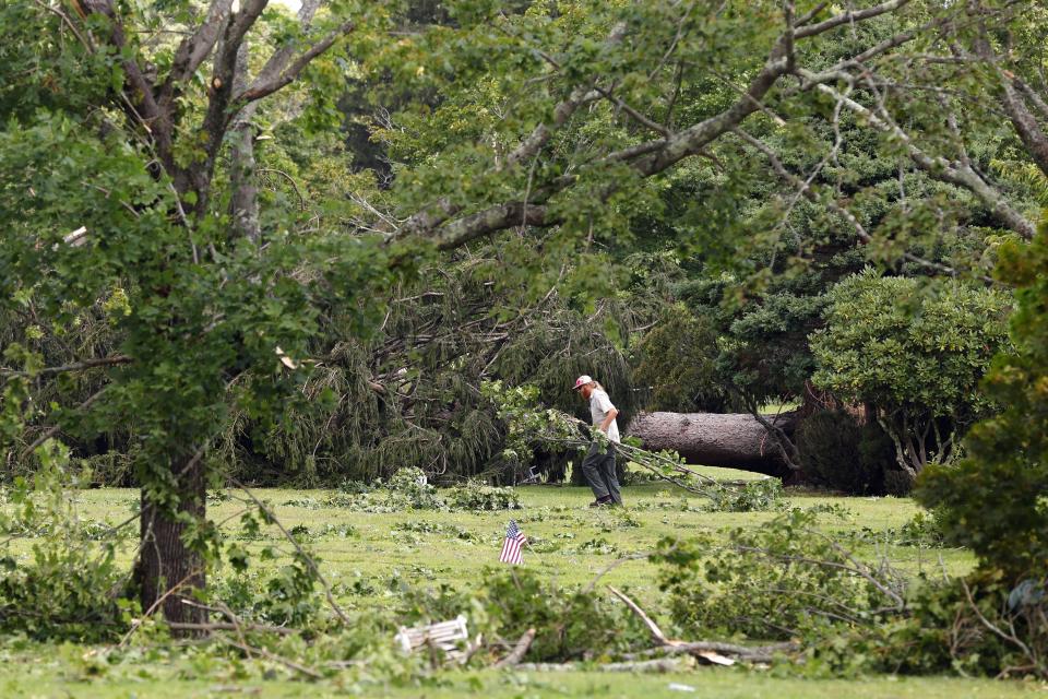 A worker at Highland Memorial Park Cemetery clears debris, Friday, Aug. 18, 2023, in Johnston, R.I., after severe weather swept through the area. (AP Photo/Michael Dwyer)