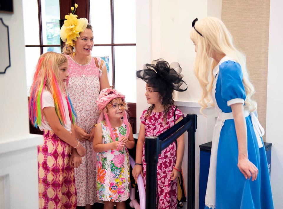 Sydney Mee and her daughters Everly, 9, from left, Sylvie, 5, and Phoebe, 7, talk to an Alice in Wonderland performer during the Mad Hatter Tea Party at the Mandel Recreation Center in Palm Beach.