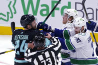 Vancouver Canucks' Oliver Ekman-Larsson (23) and Brock Boeser (6) move in to scuffle with Seattle Kraken's Jamie Oleksiak during the first period of an NHL hockey game Saturday, Oct. 23, 2021, in Seattle. (AP Photo/Elaine Thompson)