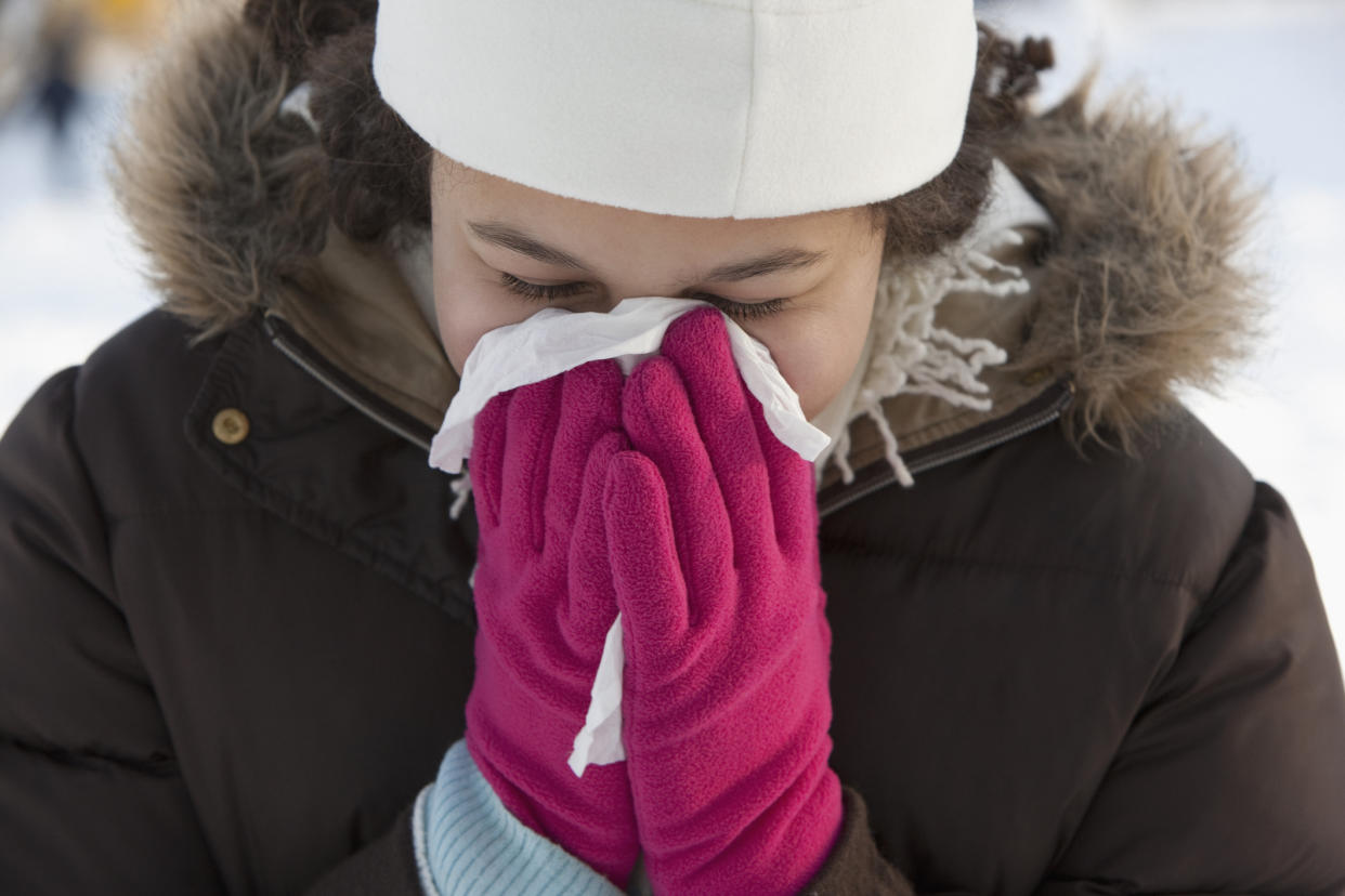 Woman blowing her nose outdoors in winter