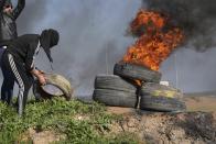 A demonstrator burns tires during a protest against Israeli military raid in the West Bank city of Nablus, along the border fence with Israel, in east of Gaza City, Wednesday, Feb. 22, 2023. Palestinian officials say several Palestinians have been killed and over a hundred were wounded during a rare daytime Israeli army arrest raid in the occupied West Bank. The Palestinian Health Ministry says a 72-year-old man was among the dead. The raid took place on Wednesday in the city of Nablus, a scene of frequent military activity. (AP Photo/Adel Hana)