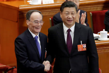 Chinese President Xi Jinping (R) shakes hands with newly elected Chinese Vice President Wang Qishan at the fifth plenary session of the National People's Congress (NPC) at the Great Hall of the People in Beijing, China March 17, 2018. REUTERS/Jason Lee