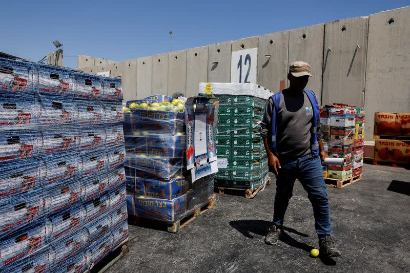 A man walks next to humanitarian aid destined for the Gaza Strip, at the Kerem Shalom crossing