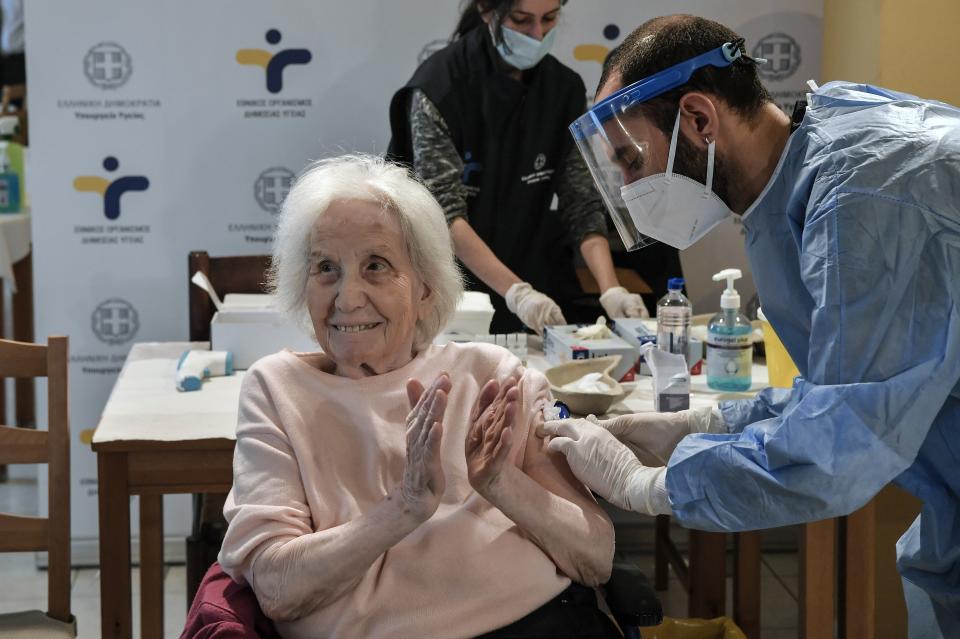 An elderly woman applauds during a vaccination at a nursing house in Athens, Monday, Jan. 4, 2021. Vaccinations were expanded from 9 to 50 hospitals nationwide on Monday. (Louisa Gouliamaki/Pool via AP)