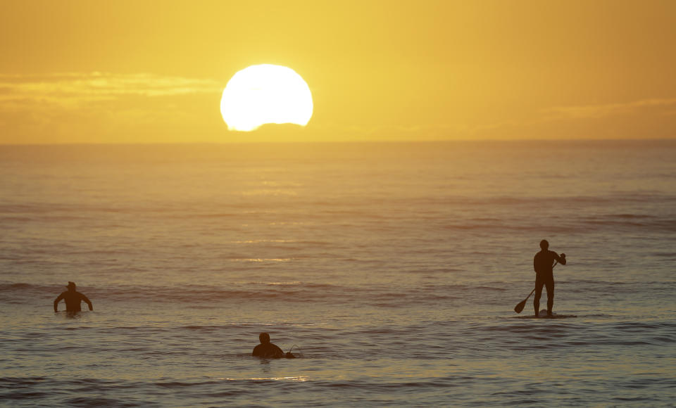 Surfers enjoy a sunrise surf at Sumner Beach as level four COVID-19 restrictions are eased in Christchurch, New Zealand, Tuesday, April 28, 2020. New Zealand eased its strict lockdown restrictions to level three at midnight to open up certain sections of the economy but social distancing rules will still apply. (AP Photo/Mark Baker)