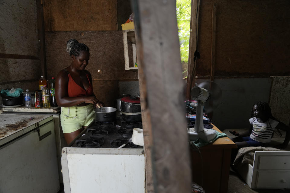 Francielle de Santana, left, cooks using the last gas canister she has, as her daughter Marcela, 8, watches a cellphone at their home in the Jardim Gramacho favela of Rio de Janeiro, Brazil, Monday, Oct. 4, 2021. Due to the rise in gas prices, Santana says she’ll have to go around scraping for any recyclable material to sell to be able to afford to buy a new gas cylinder to cook. (AP Photo/Silvia Izquierdo)