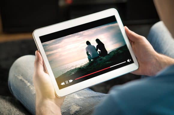 A man holding a tablet streaming video.