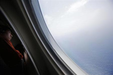 A Japan Coast Guard looks out of the window of a Gulfstream V Jet aircraft customized for search and rescue operations during a search for the missing Malaysia Airlines MH370 plane over the waters of the South China Sea March 15, 2014.REUTERS/Edgar Su