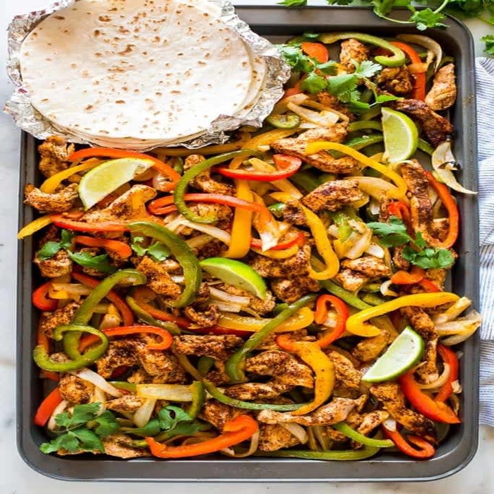 Chicken and peppers and tortillas on a sheet pan.