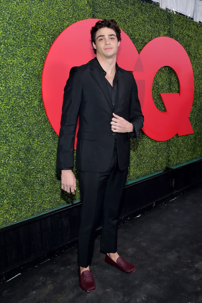Noah Centineo poses in a black suit and loafers at the GQ event