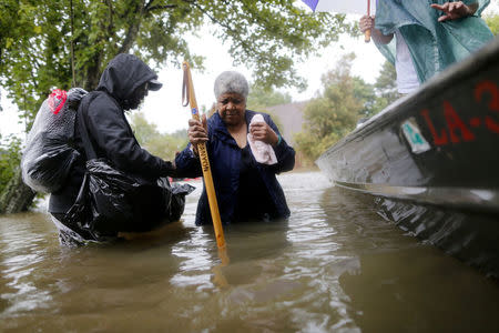 Andrew Mitchell helps his neighbor Beverly Johnson onto a rescue boat to escape the rising flood waters from Tropical Storm Harvey in Beaumont Place, Houston, Texas, U.S., on August 28, 2017. REUTERS/Jonathan Bachman