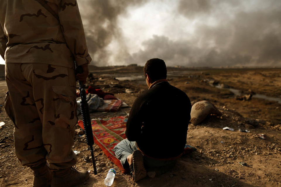 An Iraqi soldier stands next to a detained man