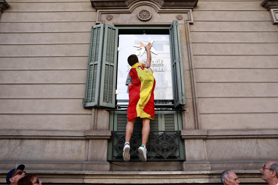 <p>A youth draped in a Spanish flag puts flag stickers on a Caixabank building before a mass rally against Catalonia’s declaration of independence, inÂ Barcelona, Spain, Sunday, Oct. 29, 2017. (Photo: Gonzalo Arroyo/AP) </p>