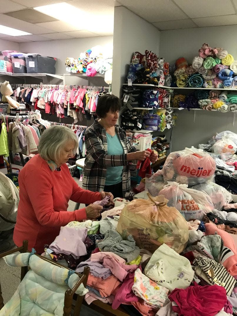 Margaret Horvath (left) and volunteer Wendy Brooks sort through sweaters and sleeping wear in the Shelly Ratz clothing closet at Heartbeat of Monroe.