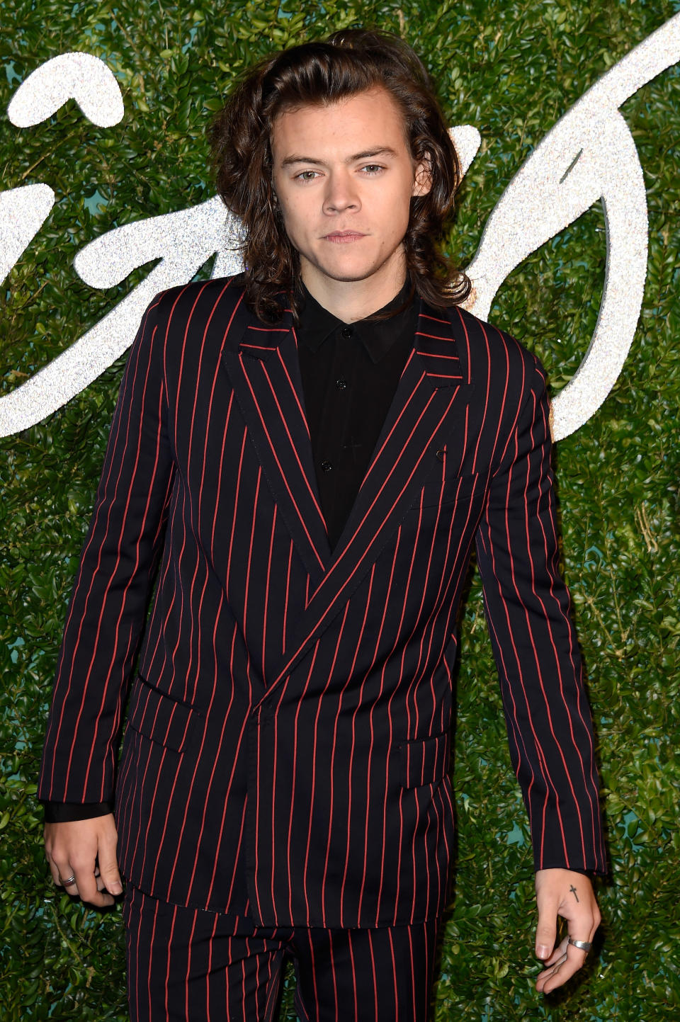 his hair is shoulder-length and he's wearing a pinstripe suit