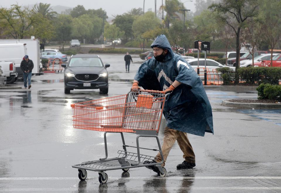 Jesse Canales, an employee at the Home Depot in Thousand Oaks, brings carts in from the rain on Monday.