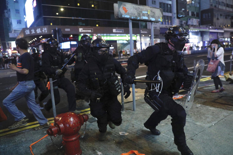 Police officers run as they confront protesters during a rally in Hong Kong on Sunday, Oct. 27, 2019. Hong Kong police fired tear gas Sunday to disperse a rally called over concerns about police conduct in monthslong pro-democracy demonstrations, with protesters cursing the officers and calling them "gangster cops." (AP Photo/Kin Cheung)