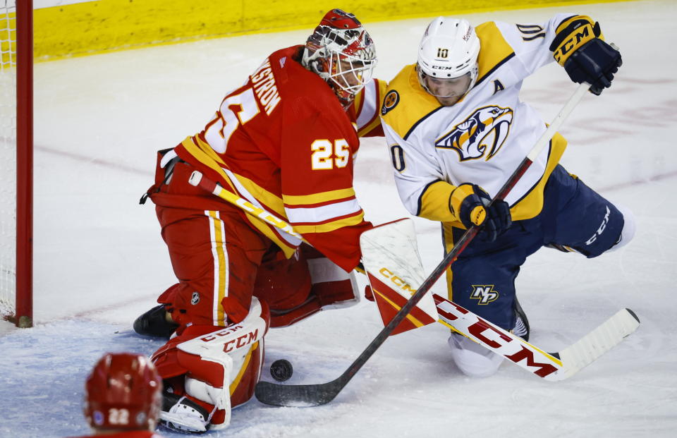 Nashville Predators forward Colton Sissons, right, tries to get the puck past Calgary Flames goalie Jacob Markstrom, left, during second-period NHL hockey game action in Calgary, Alberta, Monday, April 10, 2023. (Jeff McIntosh/The Canadian Press via AP)
