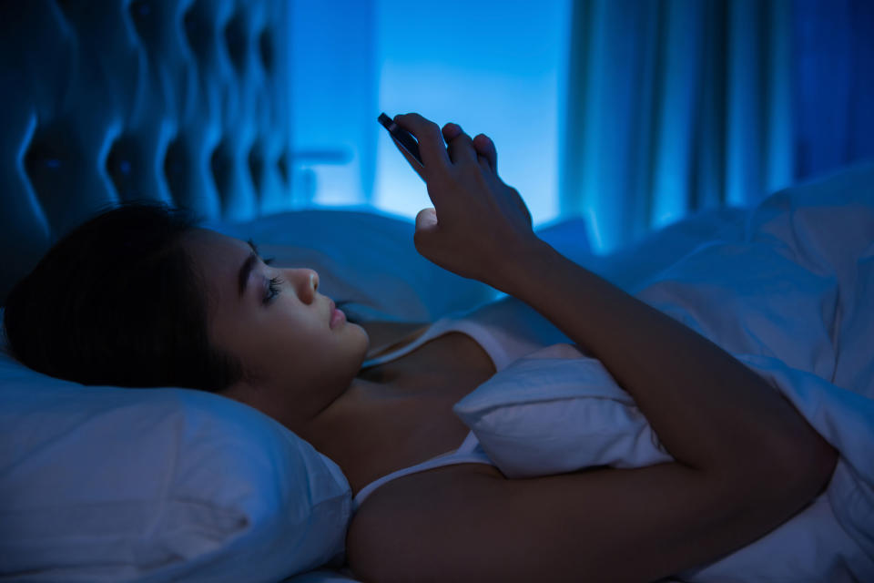 Asian women are using the smart phone on the bed before she sleeping at night. Mobile addict concept.