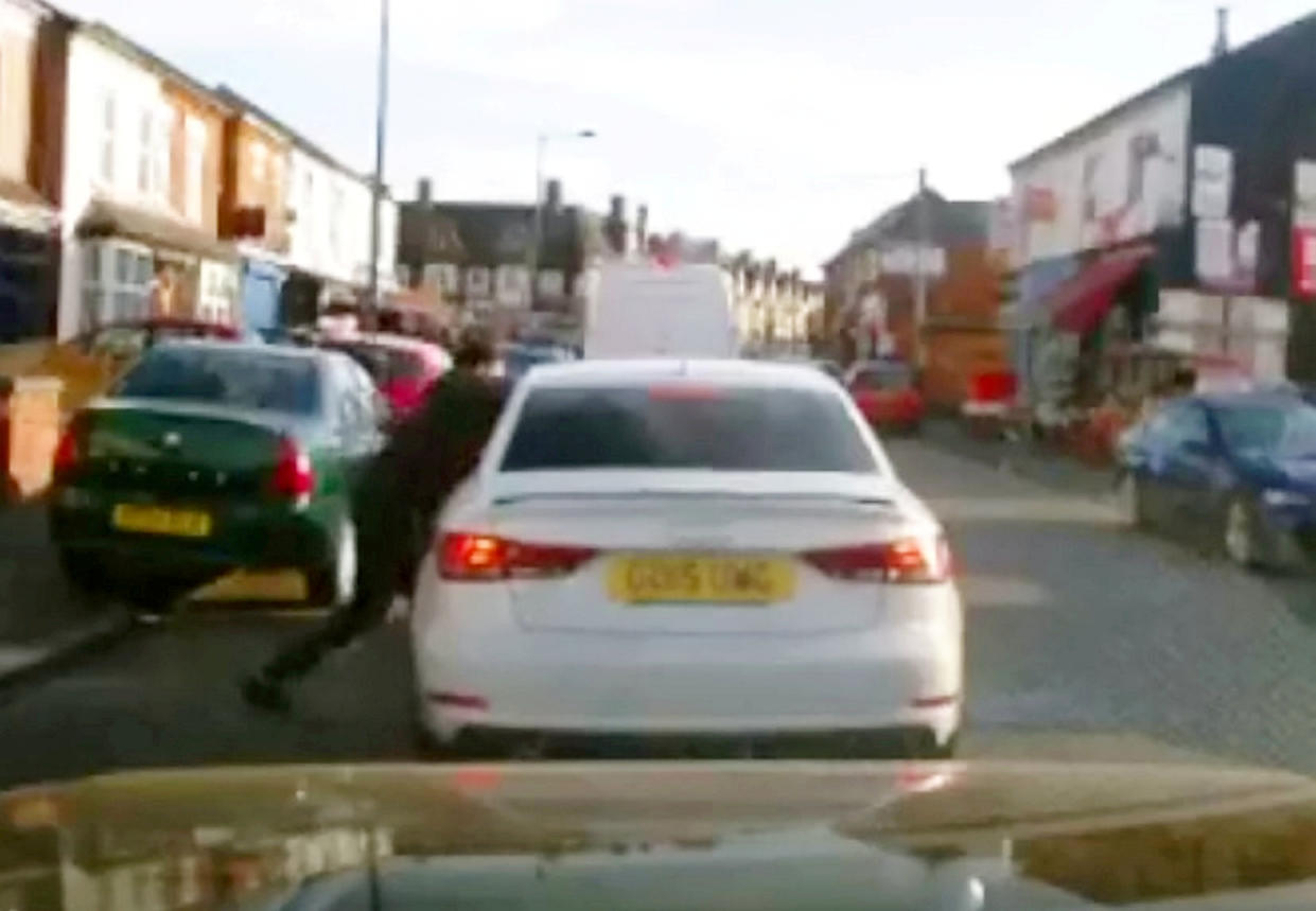Disturbing dash-cam footage shows the moment a cyclist appears to stab a car passenger with a giant blade during a shocking broad daylight knife attack. (SWNS)