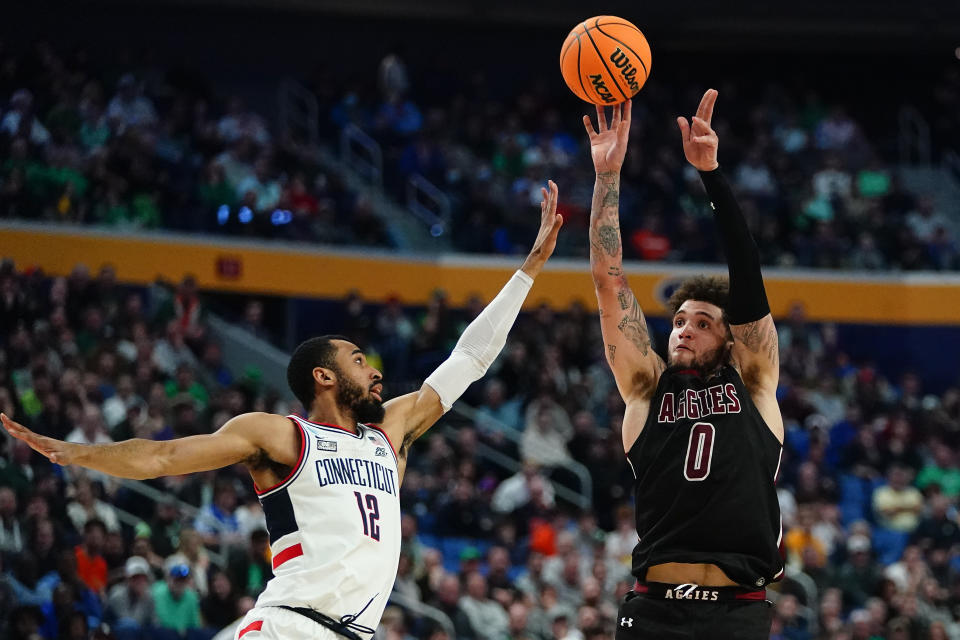 El guardia estatal de Nuevo México, Teddy Allen (0), dispara al delantero de Connecticut Tyler Polley (12) durante la segunda mitad de un partido de baloncesto universitario en la primera ronda del Torneo Masculino de la NCAA el jueves 17 de marzo de 2022 en Buffalo, Nueva York (Foto AP/ Frank Franklin II)