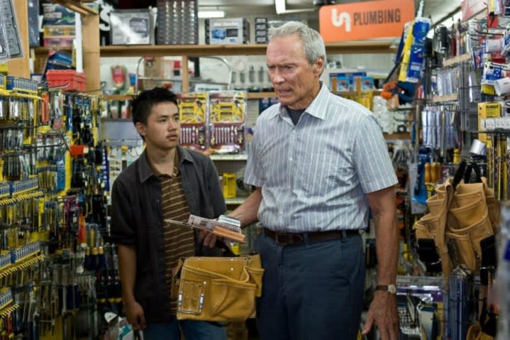 Clint Eastwood stands next to a young boy in Gran Torino.