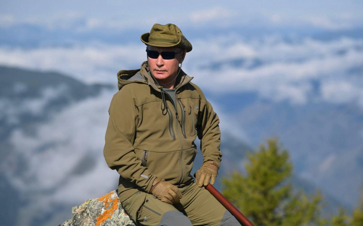 The Russian president pauses for a photograph at the top of a peak in Tyva he said was almost 6,500 feet high - REX