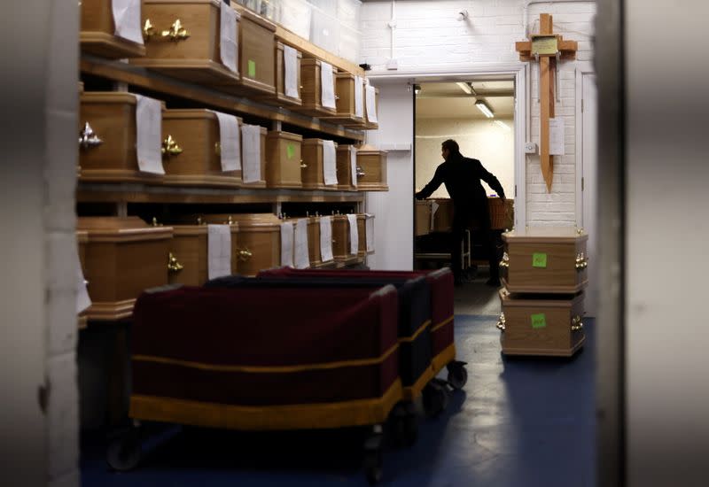 A funeral director moves coffins containing the bodies of deceased people in the mortuary at W. Uden & Sons Family Funeral Directors in Sidcup, amid the coronavirus disease (COVID-19) pandemic, in south east London