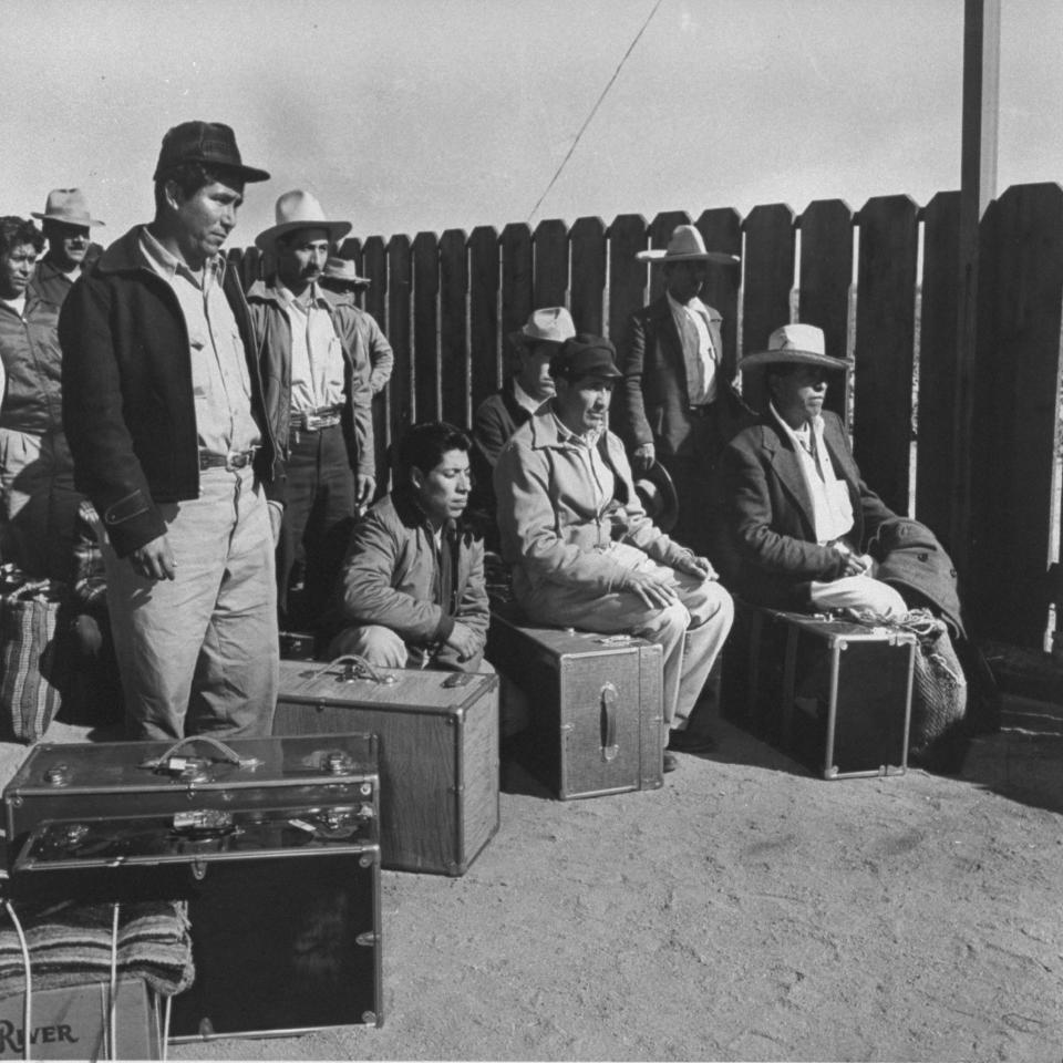 Mexican farm laborers standing on the Mexican side of the border trying to get into the U.S.