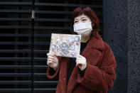 Japanese hairstylist Akina Nasu wearing a face mask shows a picture she got when she went to see the film “Demon Slayer,” which has become the nation’s top-grossing film, and opened in Miami to be eligible for the 2021 Academy Awards, in Tokyo Wednesday, March 3, 2021. Nasu and other fans says they identify with the story because of the hardships and fears during the coronavirus pandemic. (AP Photo/Yuri Kageyama)