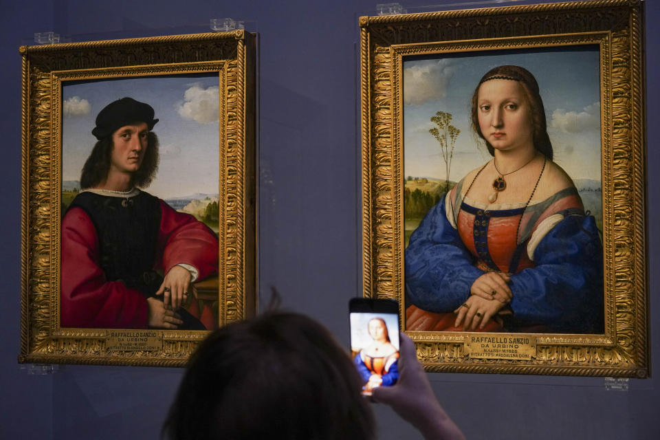 A member of the media takes pictures of 15th century paintings "Portraits of Angelo, left, and Maddalena Doni" by Raffaello Sanzio da Urbino, during a press tour of the Uffizi museum on the day off its reopening, in Florence, Wednesday, June 3, 2020. The Uffizi museum reopened to the public after over two months of closure due to coronavirus restrictions. (AP Photo/Andrew Medichini)