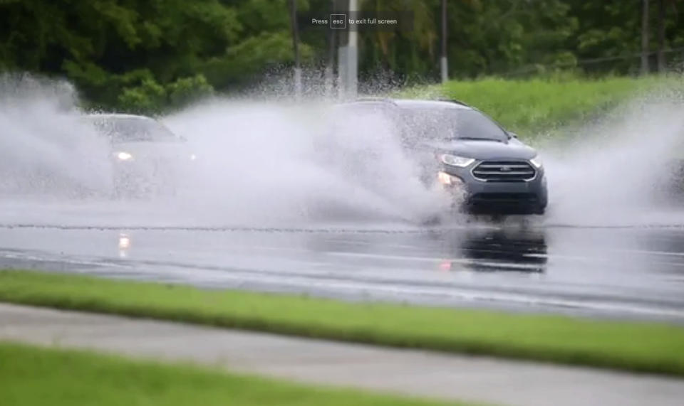 In this image made from video, cars drive through high water on a road in Canovanas, Puerto Rico, Thursday, July 30, 2020. Tropical Storm Isaias knocked out power and caused flooding and small landslides across Puerto Rico and the Dominican Republic on Thursday as forecasters predicted it would strengthen into a hurricane while moving toward the Bahamas and U.S. East Coast.(AP Photo)