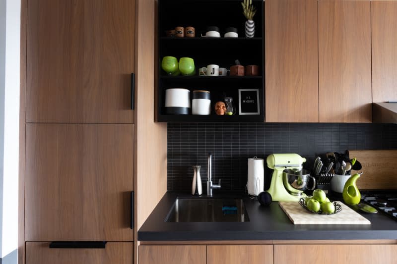 Kitchen with wood cabinets, black tile and countertops, green accents