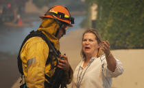 A Palisades resident talks with a firefighter before evacuating her home as a wildfire erupts in the Pacific Palisades area of Los Angeles, Monday, Oct. 21, 2019. (AP Photo/Christian Monterrosa)