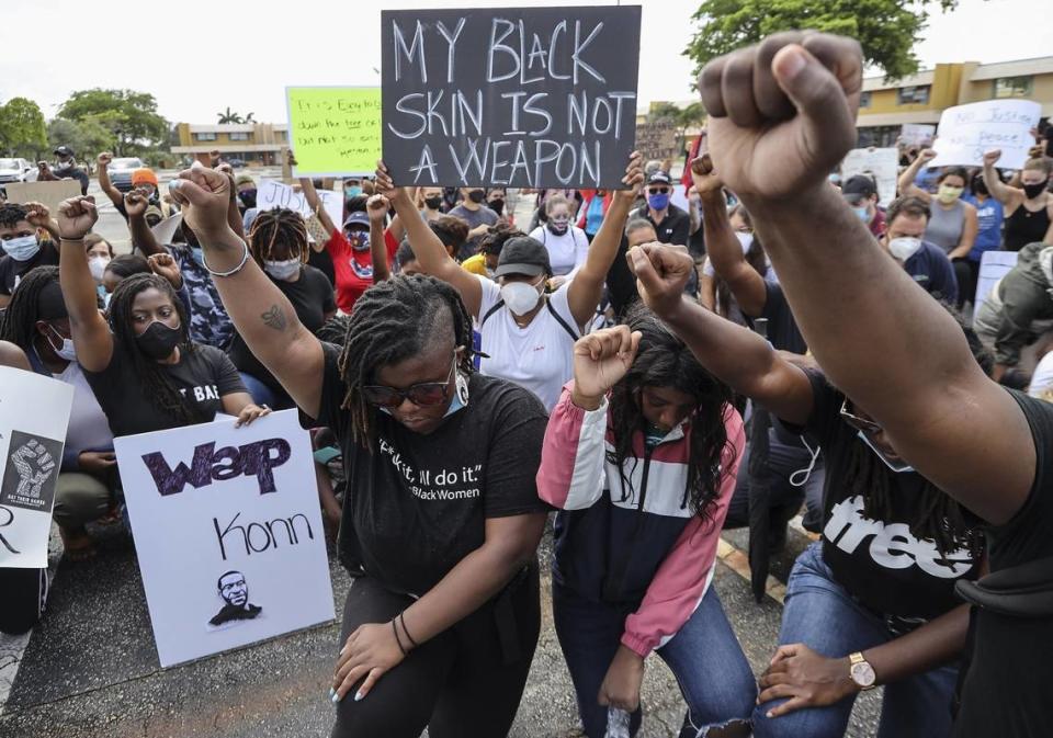 Dozens of protesters kneel and raise their fists in tribute to George Floyd and other victims of police brutality, Tuesday, June 2, 2020, in Coral Springs, Florida. The banner reads “My black skin is not a weapon.”
