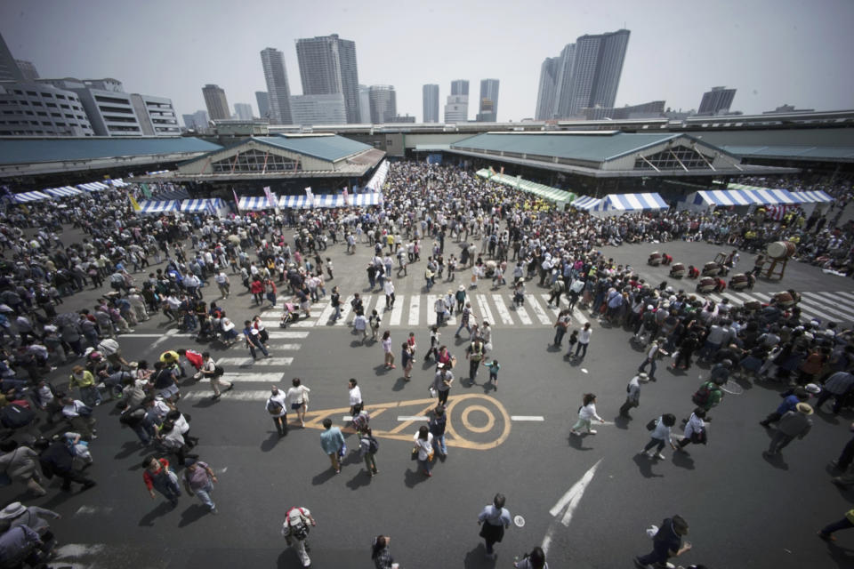 FILE - People visit a festival at the Tsukiji fish market in Tokyo, May 3, 2016. The site of Tokyo’s famed Tsukiji fish market, left empty after it was razed six years ago, will be replaced by a scenic waterfront stadium and glistening skyscrapers according to plans for its redevelopment that are facing some staunch opposition. (AP Photo/Eugene Hoshiko, File)