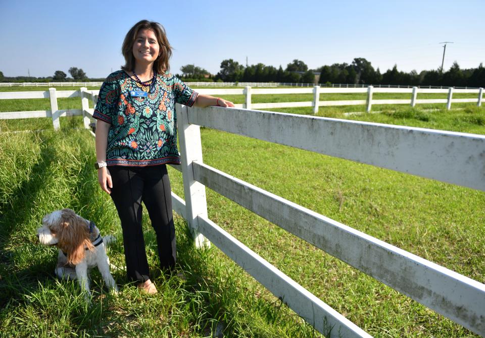 Sidney Turner is founder and chair of the board of directors at Resilient Retreat.  She stands, with her therapy dog, Journey, next to one of the pastures where they plan to offer equine therapy programs. Resilient Retreat will provide free evidence-based programs for those impacted by trauma and abuse. 