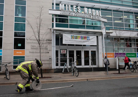 A firefighter rolls up a hose after a threat made to the Miles Nadal Jewish Community Centre was deemed a hoax in Toronto, Ontario, Canada, March 7, 2017. REUTERS/Chris Helgren