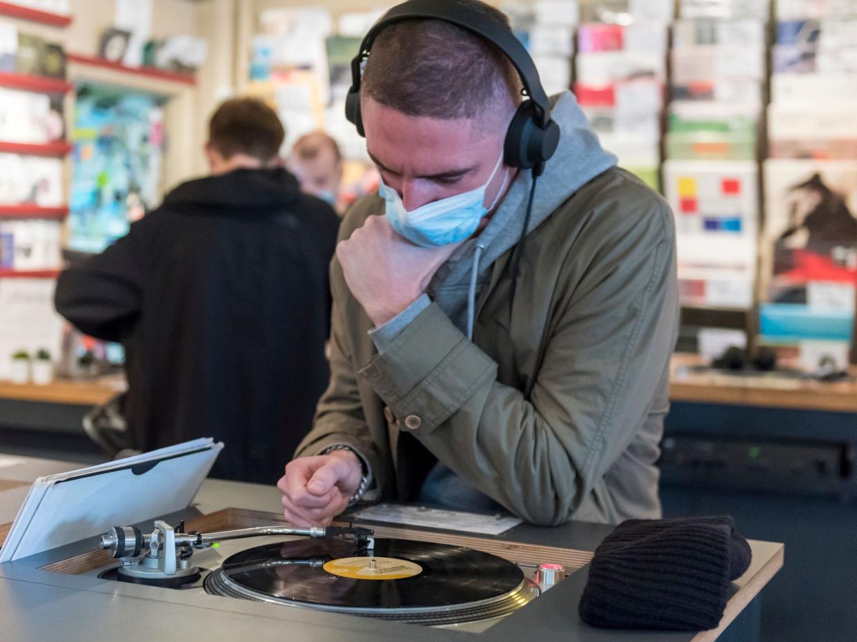 A customer wears a facemask while listening to a vinyl record in Soho, London (Rex Features)