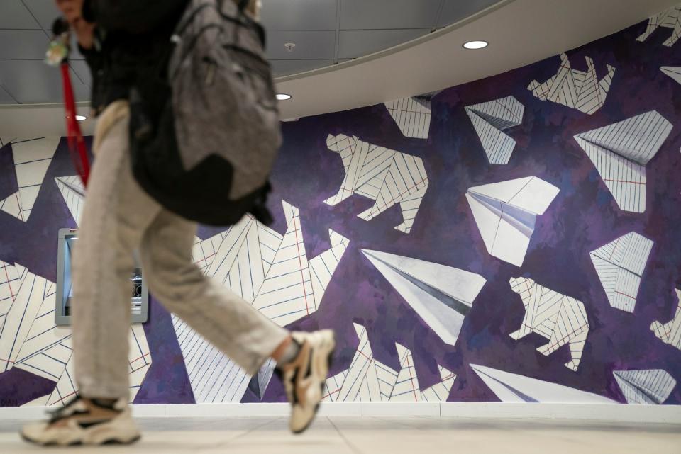 Students walk by the "Soar" mural by Ani Garabedian, 47, of Detroit, on Monday, Jan. 22, 2024. The mural was commissioned by Tansley Stearns the president and CEO of Community Financial Credit Union in the Wayne State University student center. The mural pays homage to a long lost tradition at Wayne State of students throwing dagger-sharp paper airplanes at the ceiling of the student center.