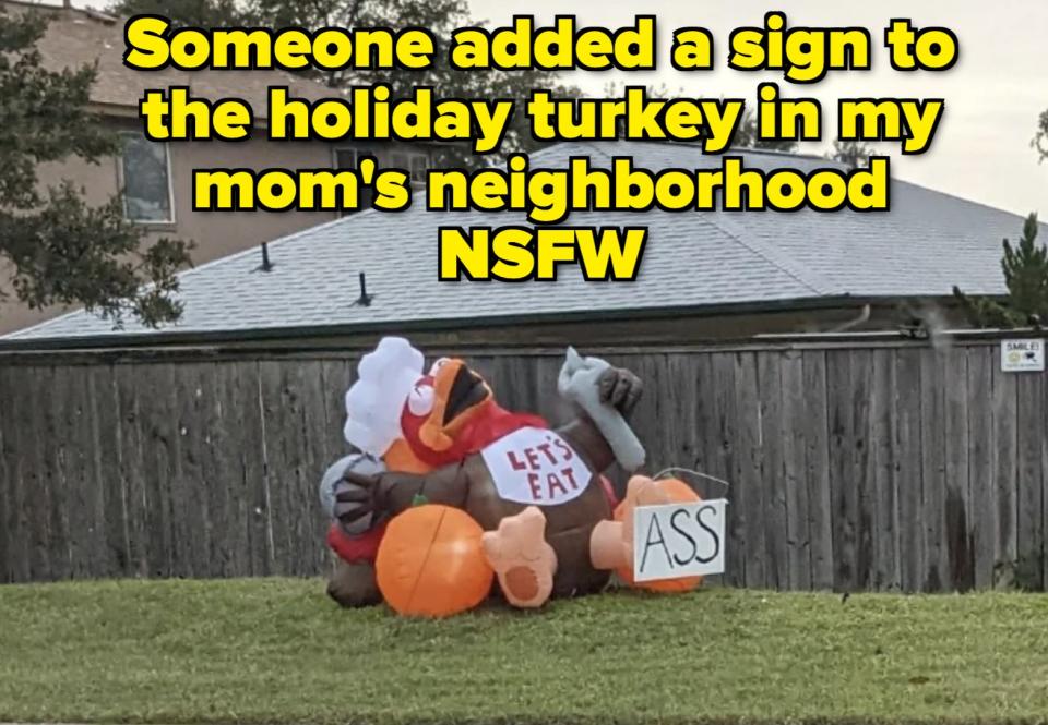 Inflatable Thanksgiving turkey lying on its back in a yard, holding a sign. The sign text is incomplete, spelling out "ASS."