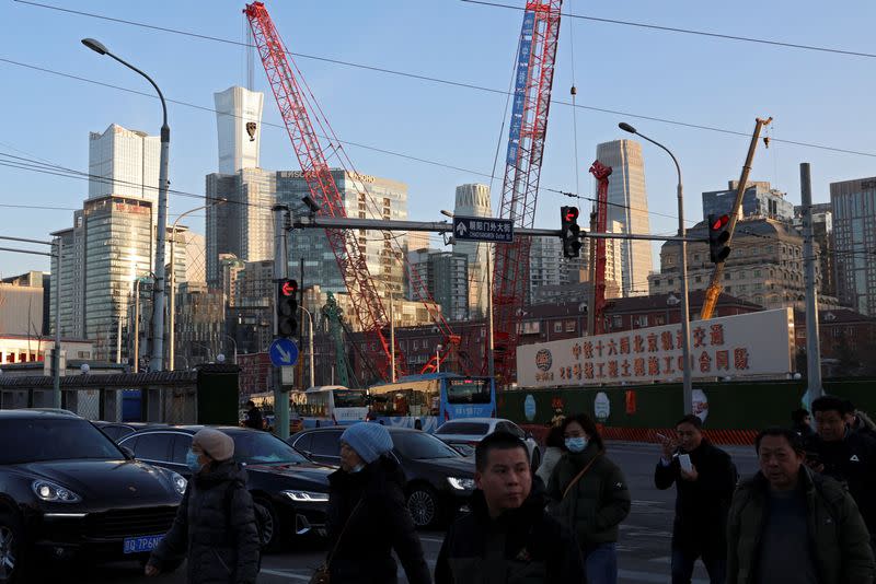 FILE PHOTO: People cross an intersection near a construction site in Beijing