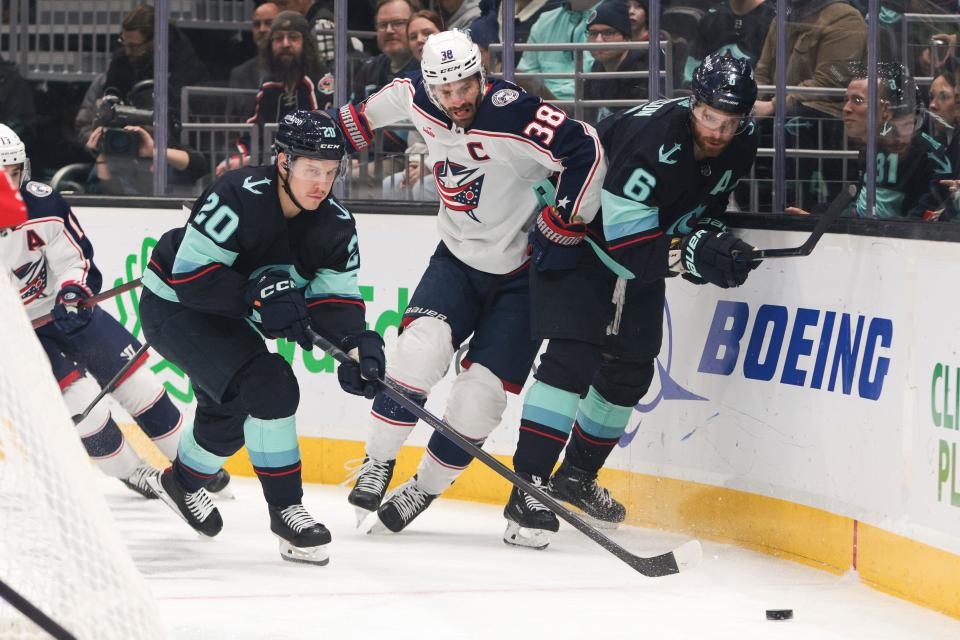 Columbus Blue Jackets center Boone Jenner (38) goes for the puck defended by Seattle Kraken right wing Eeli Tolvanen (20) and defenseman Adam Larsson (6) during the first period of an NHL hockey game Saturday, Jan. 28, 2023, in Seattle. (AP Photo/Jason Redmond)